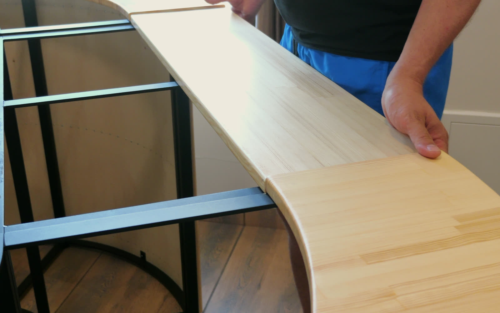 Hands lowering the pine rim board onto the steel frame