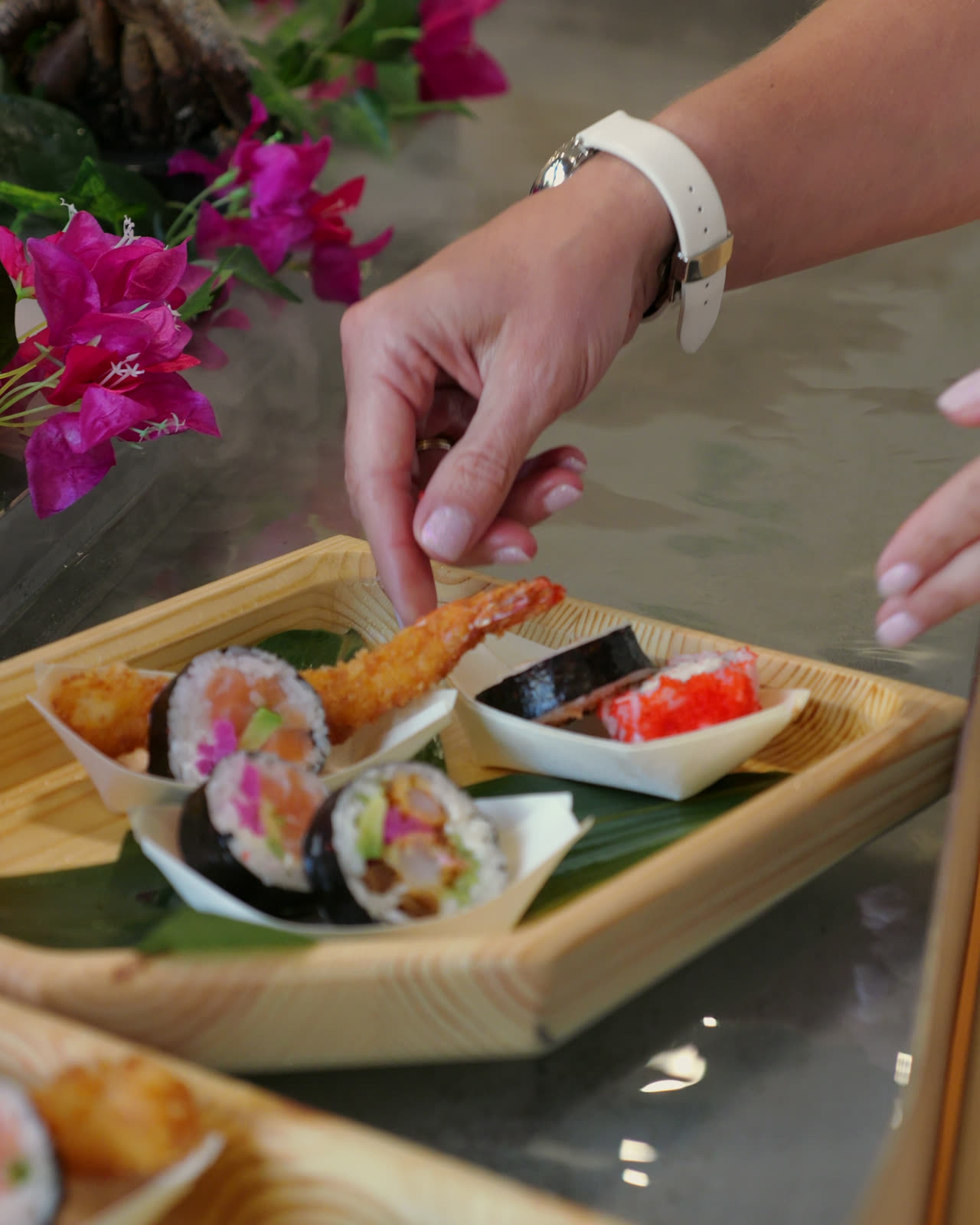 A guest's hand lifting a piece from a passing boat