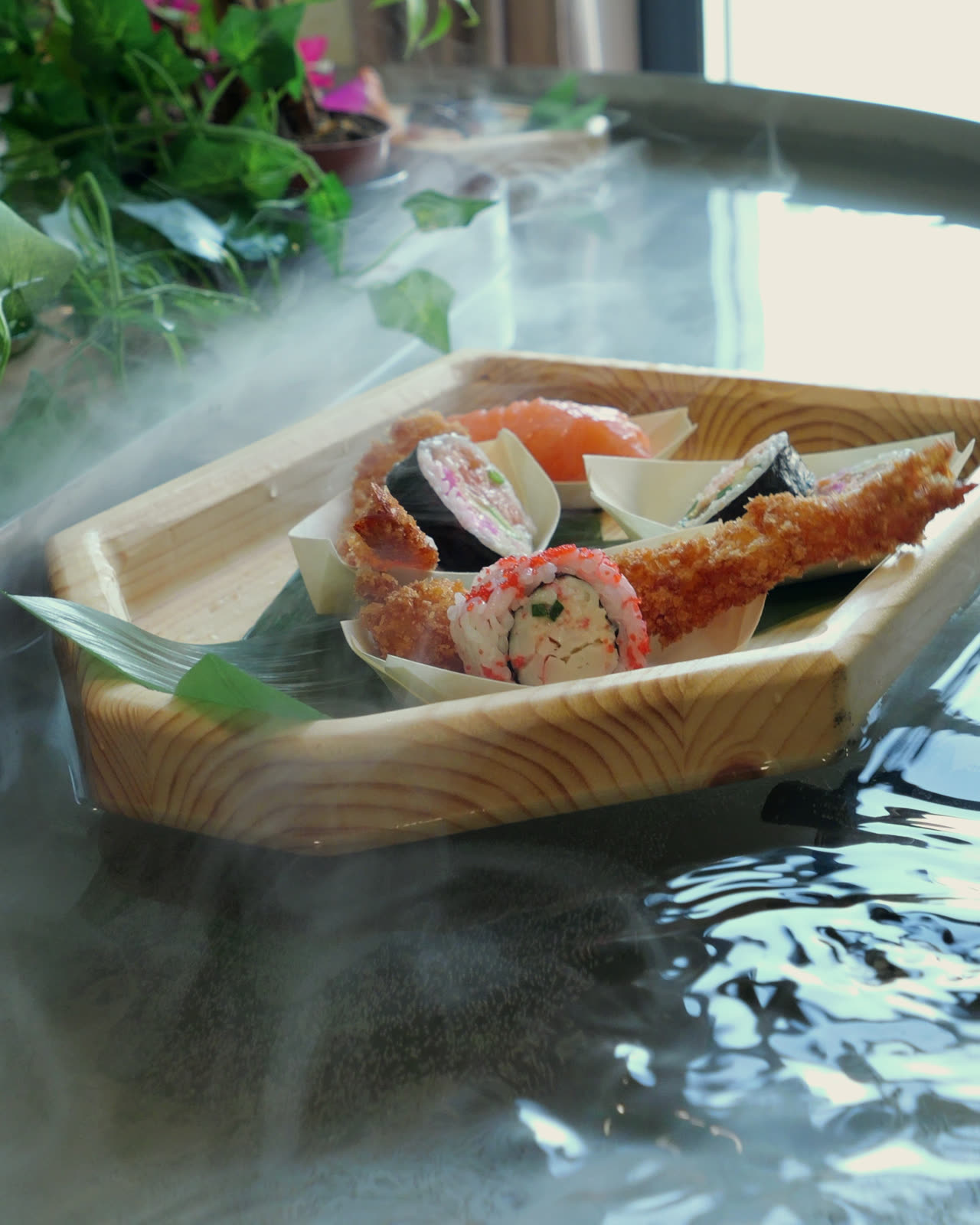 A wooden boat of sushi drifting through mist on the river